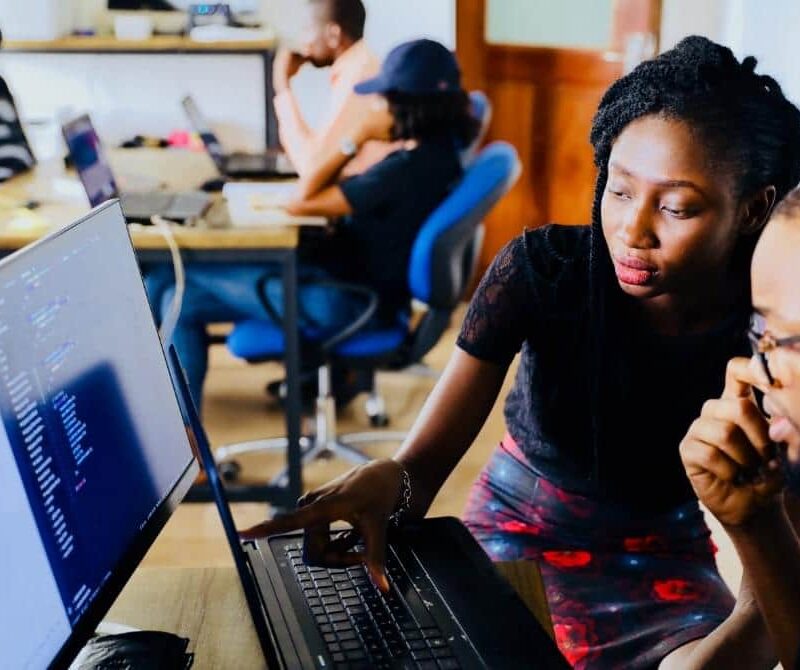 Two colleagues looking at code on a laptop screen together