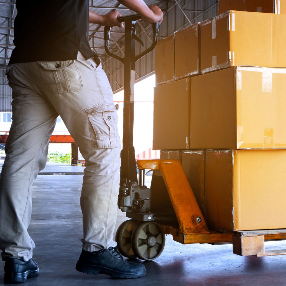 Worker walking past stacked boxes on a loading dock