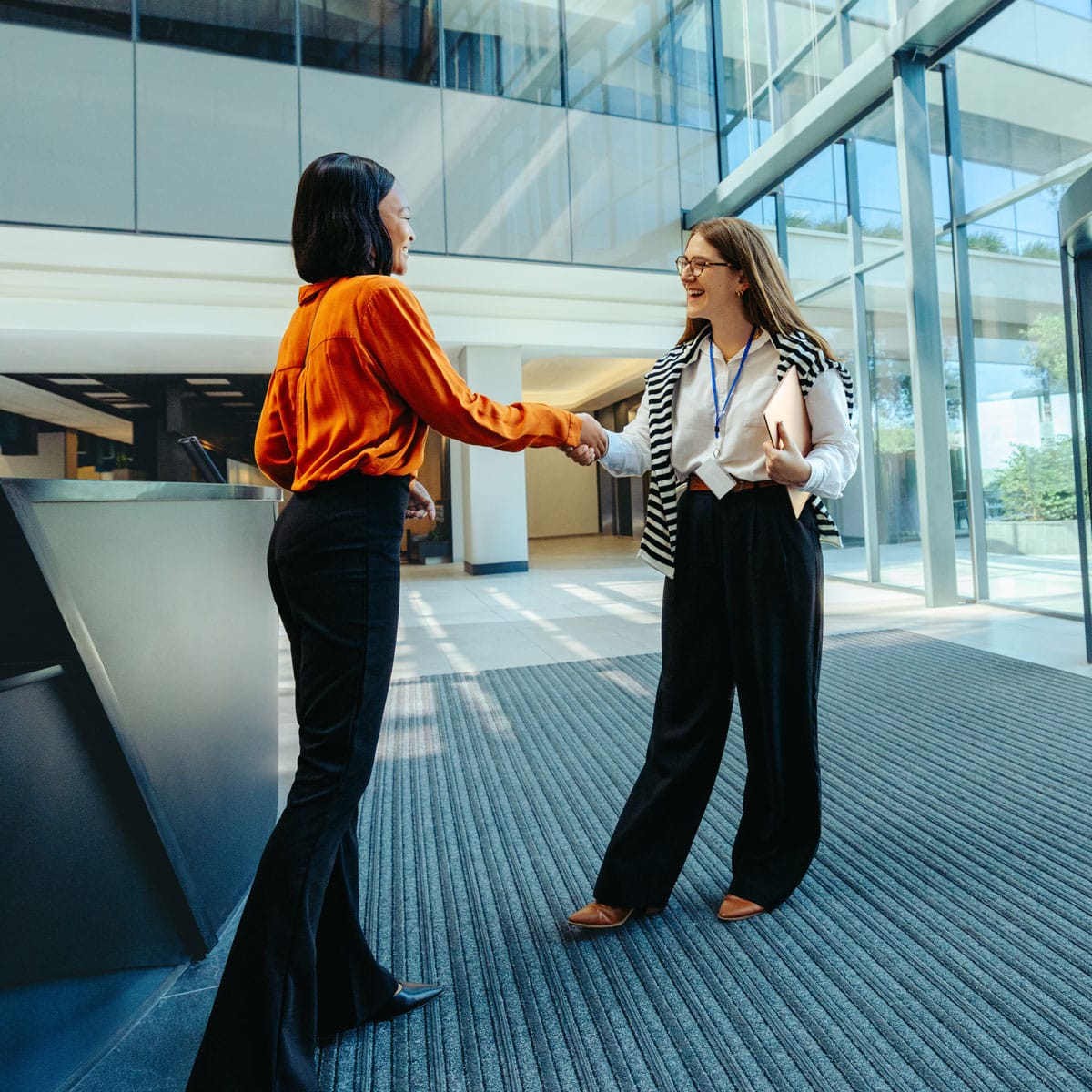 Two colleagues shaking hands in an office lobby during onboarding
