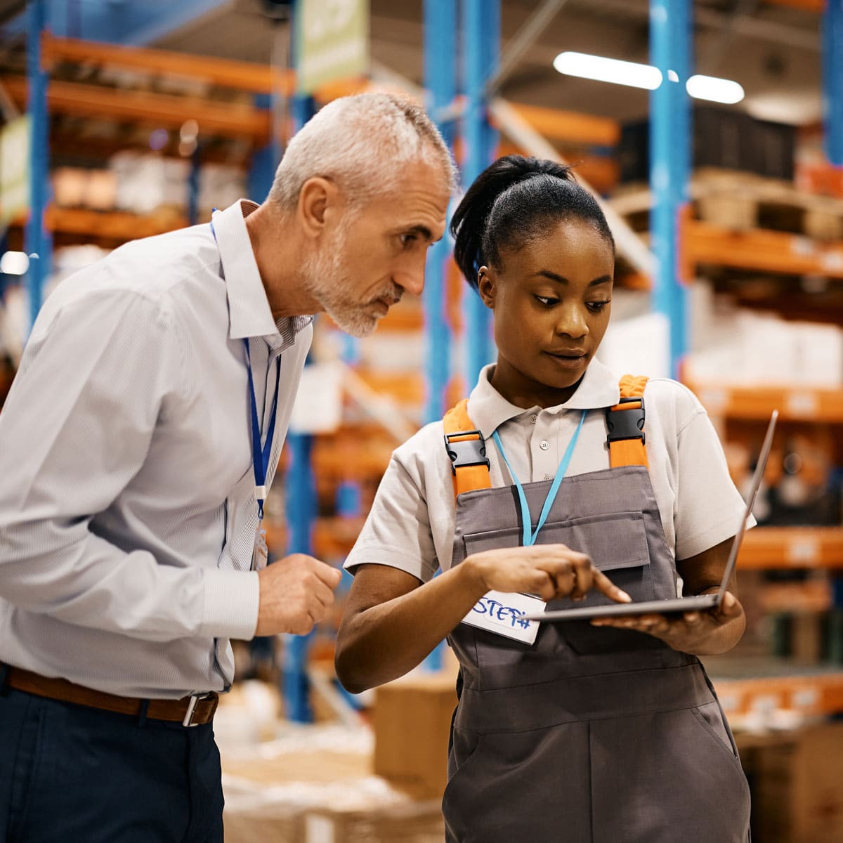 Manager and employee reviewing data on a tablet in a warehouse