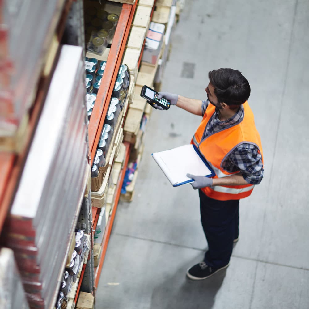 Worker in a hi-vis vest scanning shelf inventory with a handheld scanner