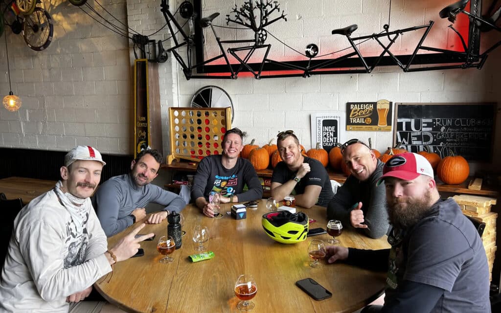 about-slider-11 Cycle Labs colleagues gathered around a table at a bike-themed venue