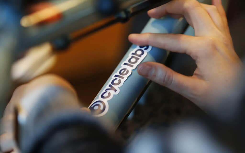 about-slider-2 Close-up of a hand adjusting a bicycle handlebar branded with the Cycle Labs logo