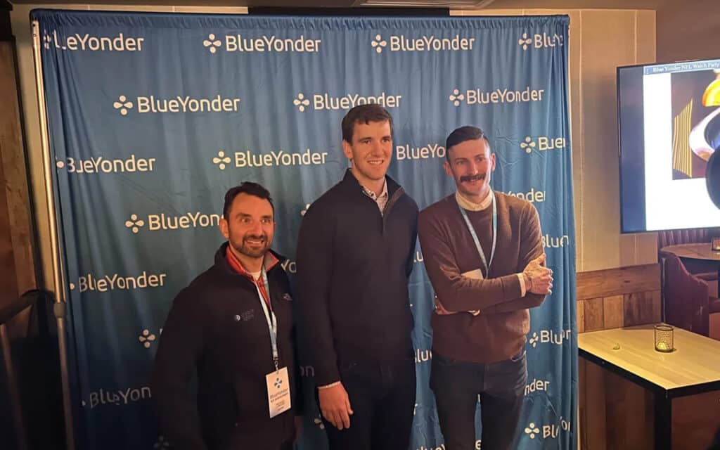 about-slider-7 Three Cycle Labs colleagues posing in front of a Blue Yonder conference backdrop