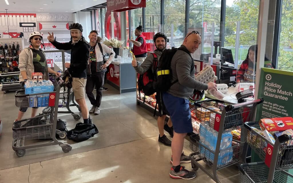 about-slider-8 Cycle Labs team playfully riding shopping carts inside a Target store
